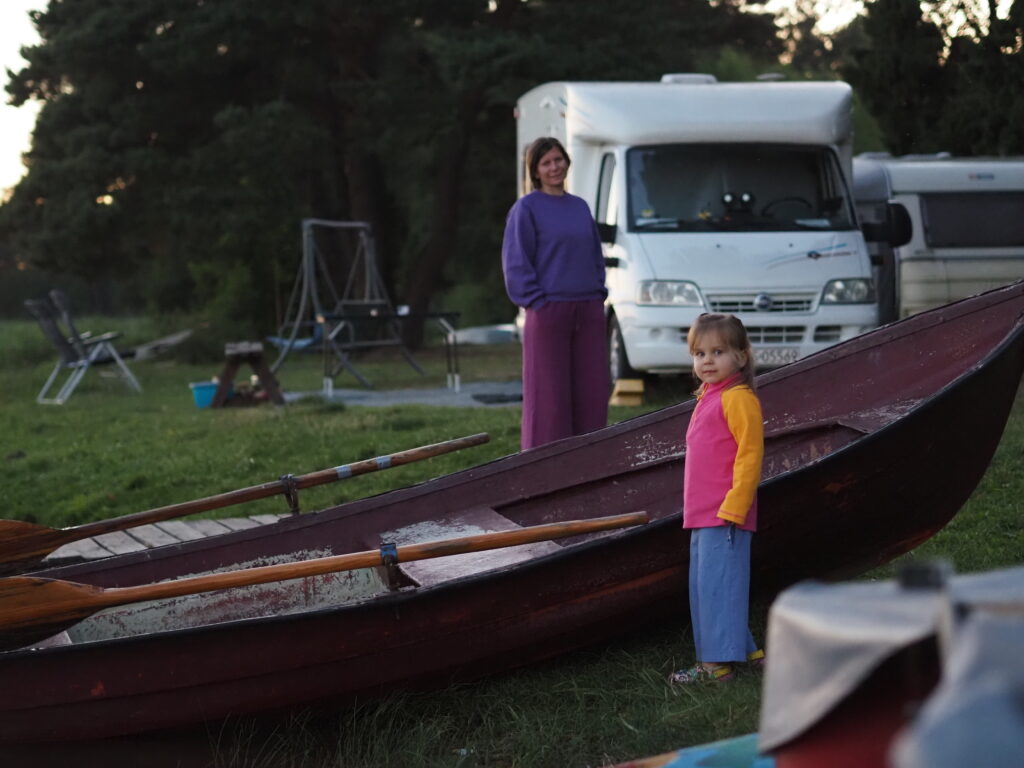 P8200398 Rodzina z dzieckiem przy kamperze nad jeziorem podczas podróży kamperem